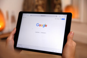 Person holding a tablet showing the Google homepage, representing how Google AI Overviews change search results for dental patients